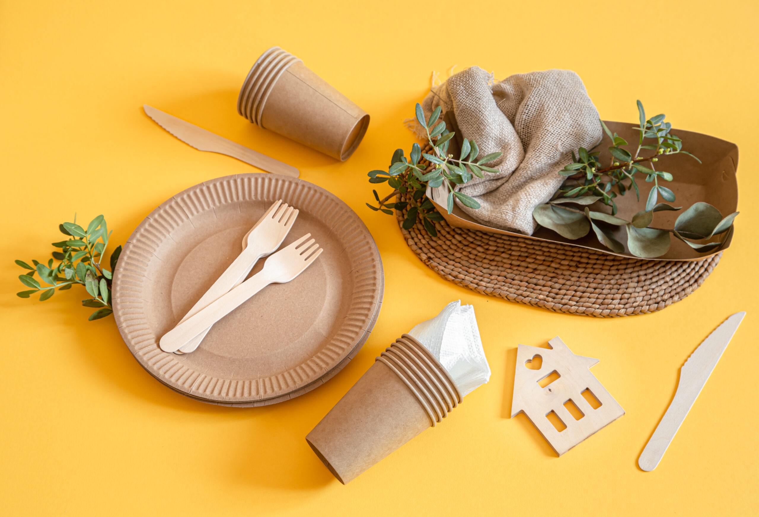 Eco-friendly, stylish recyclable paper tableware. Paper food boxes, plates, and cornstarch Cutlery on a trending orange background.
